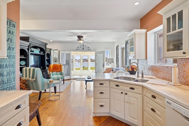 kitchen featuring a ceiling fan, dishwasher, a sink, open floor plan, and light countertops