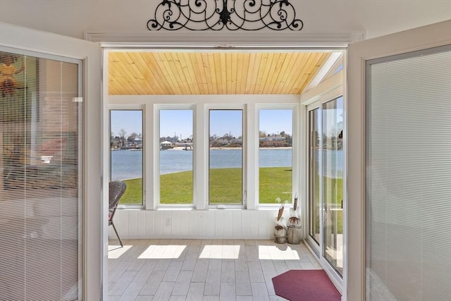 unfurnished sunroom with lofted ceiling, a water view, a wealth of natural light, and wood finished floors