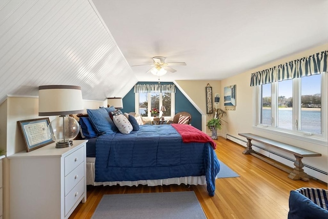 bedroom with baseboard heating, light wood-style floors, vaulted ceiling, and a ceiling fan