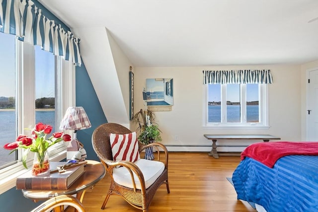 bedroom with a water view, baseboard heating, and light wood-type flooring