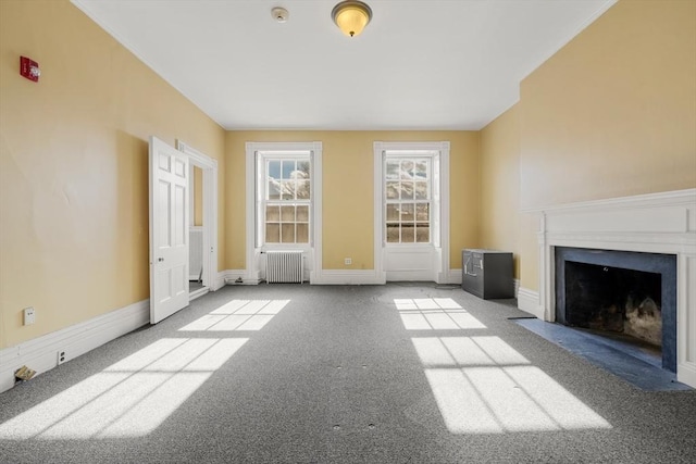 unfurnished living room featuring a fireplace with flush hearth, radiator heating unit, baseboards, and carpet floors