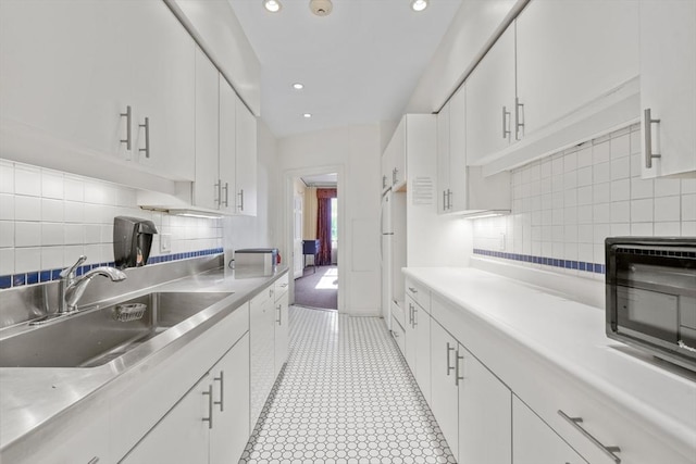 kitchen with a sink, stainless steel countertops, white cabinetry, recessed lighting, and white appliances