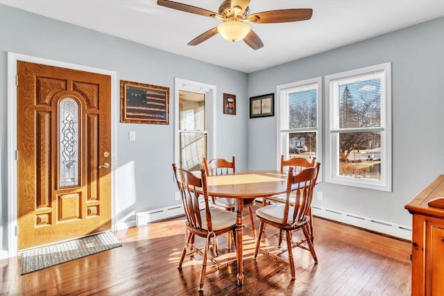 dining area featuring hardwood / wood-style flooring, ceiling fan, and a baseboard heating unit