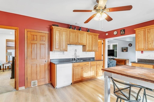 kitchen with sink, light brown cabinets, light wood-type flooring, dishwasher, and decorative backsplash