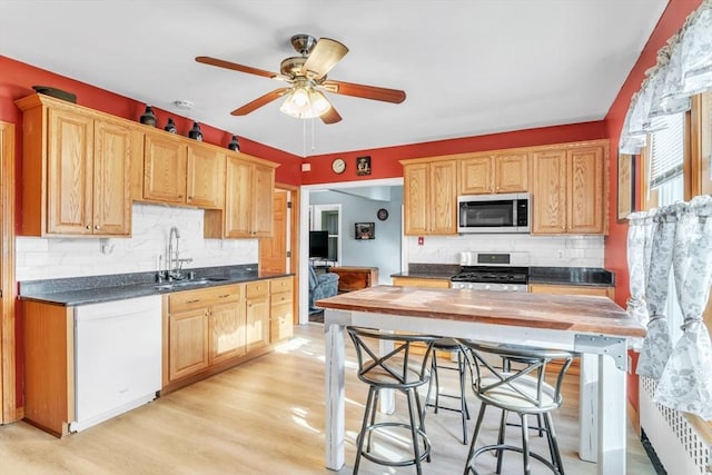 kitchen with sink, wooden counters, appliances with stainless steel finishes, light hardwood / wood-style floors, and decorative backsplash