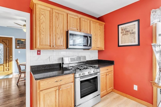 kitchen with stainless steel appliances, light hardwood / wood-style floors, dark stone counters, and decorative backsplash