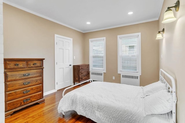 bedroom with crown molding, radiator heating unit, and wood-type flooring