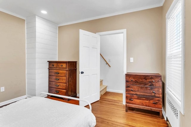 bedroom featuring ornamental molding, light hardwood / wood-style flooring, and radiator heating unit