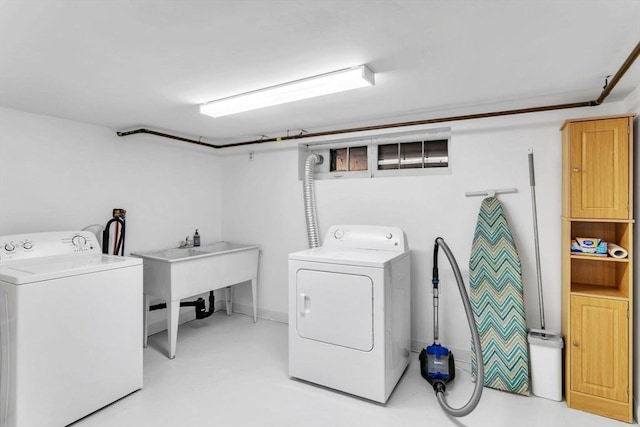 clothes washing area featuring independent washer and dryer and sink