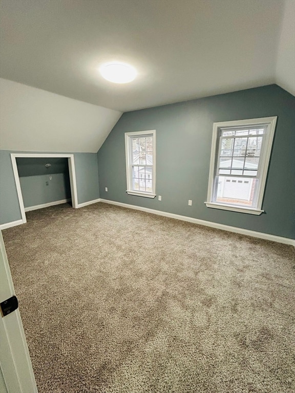 bonus room with carpet flooring and vaulted ceiling