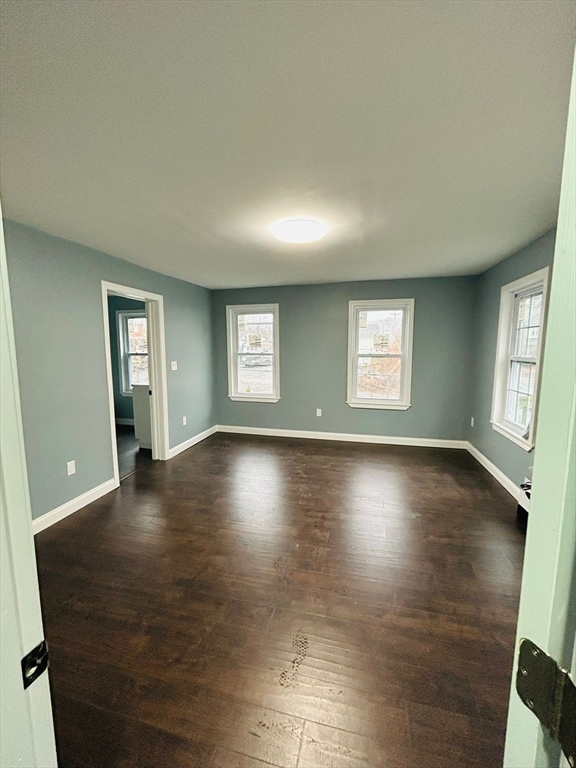 spare room featuring a wealth of natural light and dark wood-type flooring