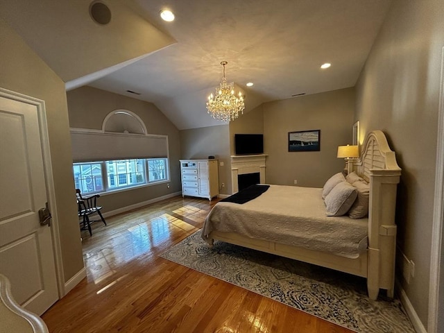 bedroom with vaulted ceiling, light hardwood / wood-style flooring, and a notable chandelier