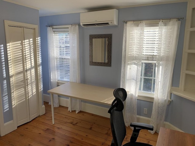 office area with ornamental molding, an AC wall unit, light wood finished floors, and baseboards