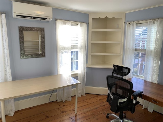 office area featuring baseboards, hardwood / wood-style floors, and a wall mounted air conditioner