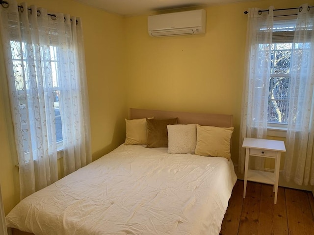 bedroom featuring wood finished floors and a wall mounted AC