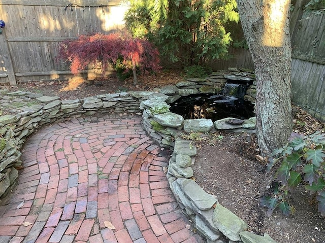 exterior space with fence and a garden pond