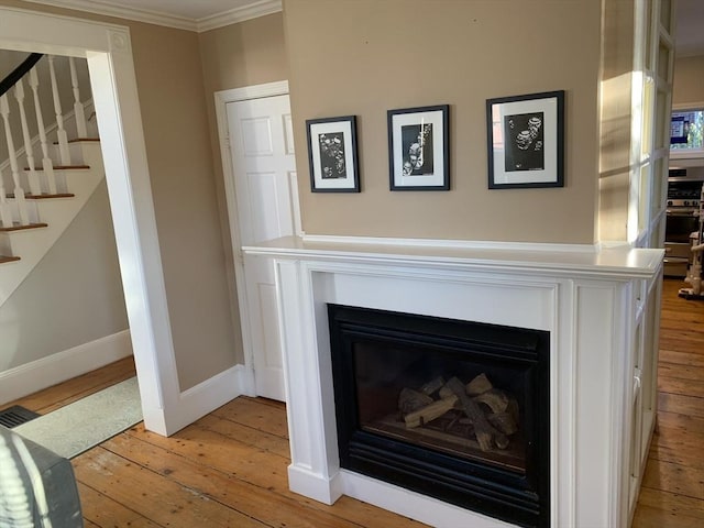 room details featuring crown molding, a fireplace, wood finished floors, stainless steel gas range oven, and baseboards