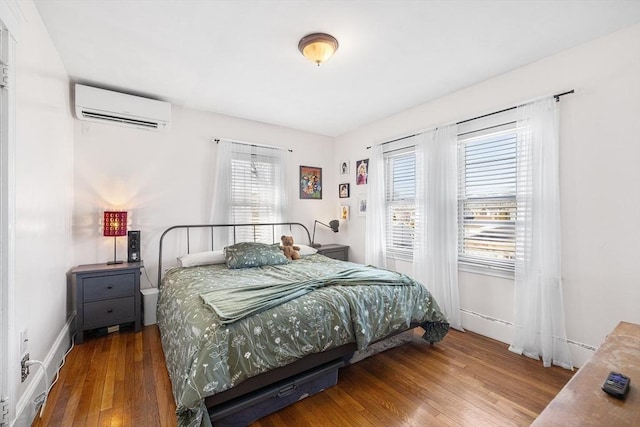 bedroom with a wall mounted air conditioner and wood finished floors