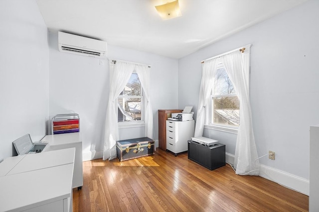 misc room featuring an AC wall unit, wood-type flooring, and baseboards