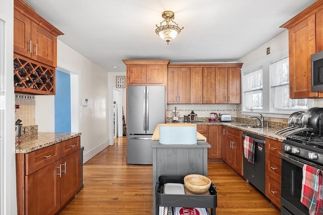 kitchen with appliances with stainless steel finishes, brown cabinets, and light stone counters