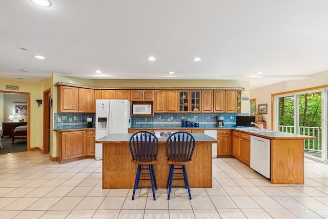 213 N Worcester St, Norton, MA 02766 - kitchen with white appliances, a peninsula, decorative backsplash, a center island, and brown cabinets