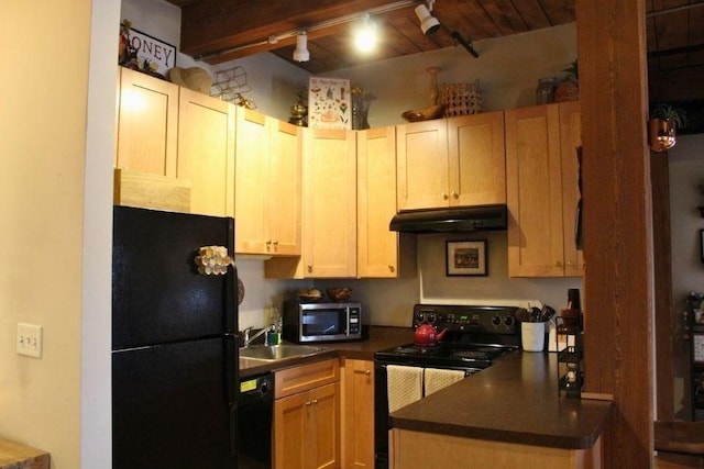 kitchen featuring under cabinet range hood, dark countertops, rail lighting, a sink, and black appliances