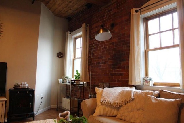 living area with plenty of natural light, wood finished floors, baseboards, and brick wall