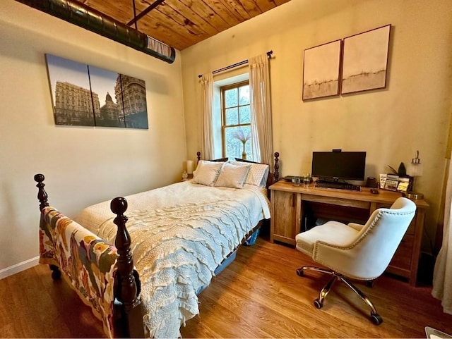 bedroom featuring baseboards, wood finished floors, and wood ceiling