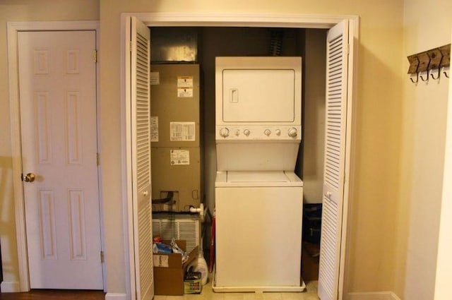 washroom with baseboards, stacked washer and dryer, and laundry area