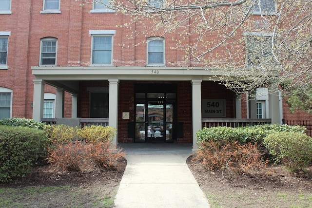 property entrance with brick siding and a porch