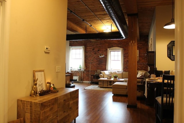 living area with wood finished floors, wooden ceiling, and brick wall