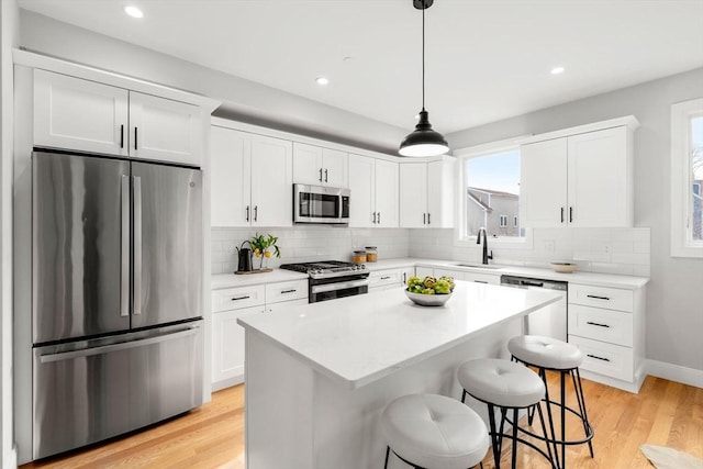 kitchen featuring pendant lighting, a breakfast bar area, a center island, a sink, and appliances with stainless steel finishes