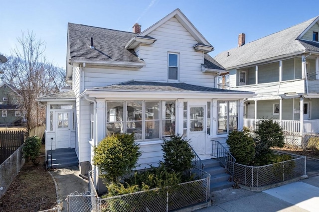 american foursquare style home featuring a fenced front yard, entry steps, and a shingled roof