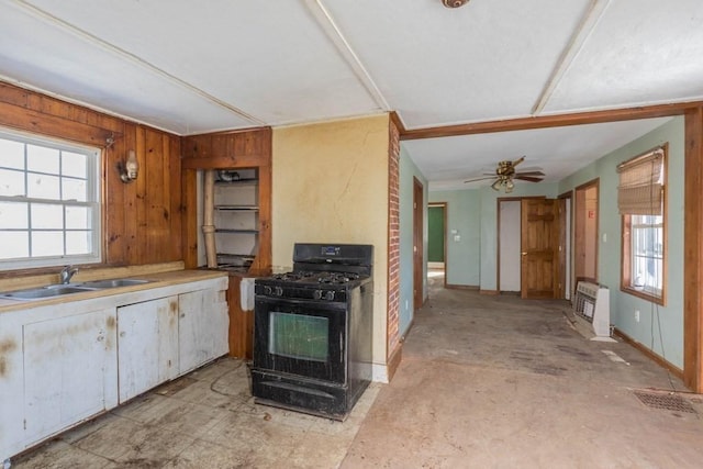 kitchen featuring sink, heating unit, a wall mounted AC, black gas range oven, and ceiling fan