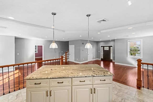 kitchen featuring cream cabinets, light wood-type flooring, pendant lighting, and a kitchen island