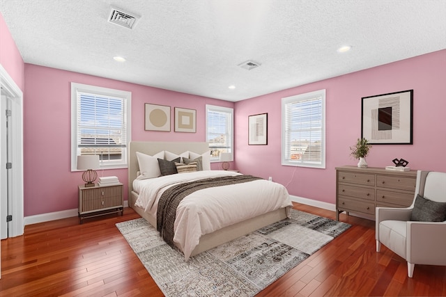 bedroom with multiple windows, dark wood-type flooring, and a textured ceiling