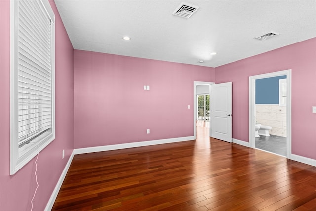 unfurnished bedroom featuring wood-type flooring, a textured ceiling, and connected bathroom