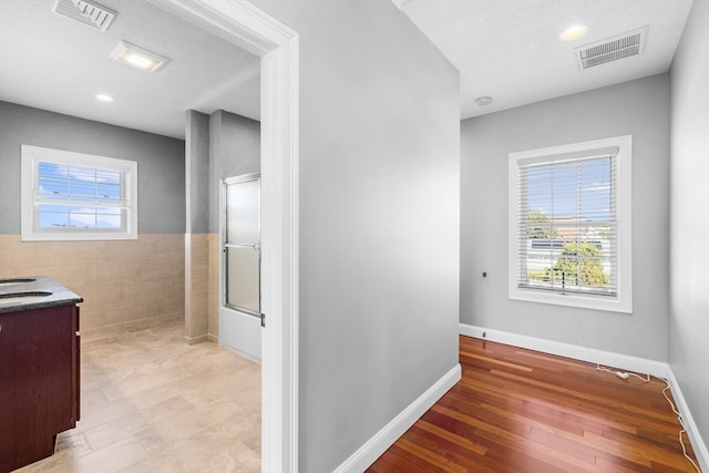 bathroom featuring wood-type flooring, tile walls, vanity, and a shower