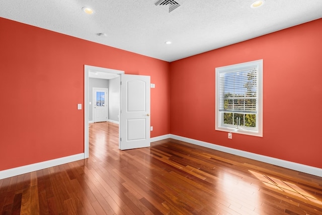 empty room featuring a textured ceiling and hardwood / wood-style floors