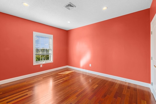 empty room with hardwood / wood-style flooring and a textured ceiling