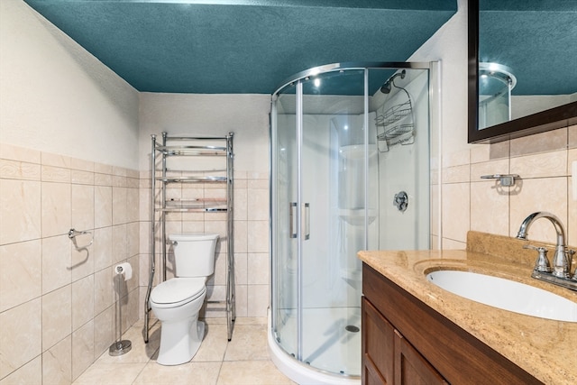 bathroom with vanity, tile walls, a shower with shower door, and toilet