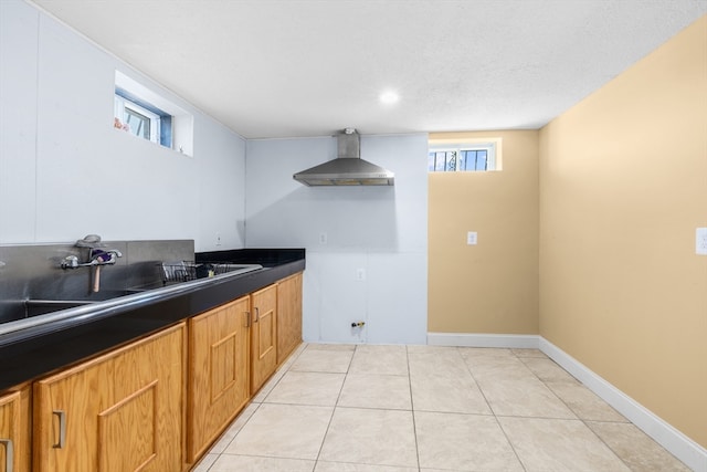 kitchen with light tile patterned floors, a textured ceiling, sink, and wall chimney range hood