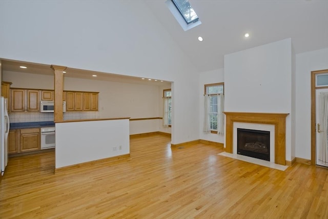 24 High Pines Cir Unit 24, Wilbraham, MA 01095 - unfurnished living room featuring high vaulted ceiling, a skylight, a fireplace with flush hearth, light wood-type flooring, and recessed lighting