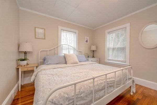 bedroom featuring crown molding, baseboards, and wood finished floors