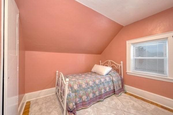 bedroom with lofted ceiling and baseboards