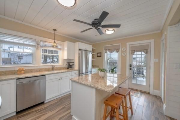 kitchen featuring a breakfast bar area, a sink, white cabinetry, ornamental molding, and appliances with stainless steel finishes