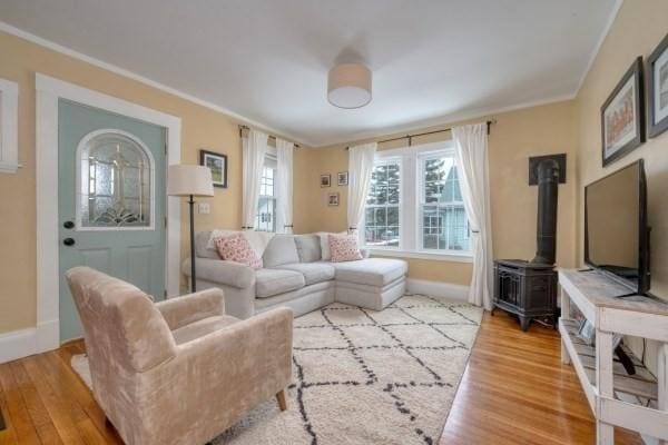 living area with a wood stove, crown molding, and wood finished floors