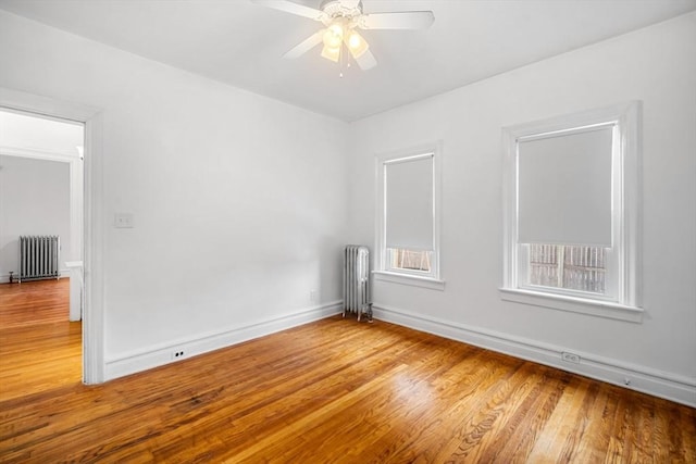 empty room with ceiling fan, radiator heating unit, and hardwood / wood-style floors