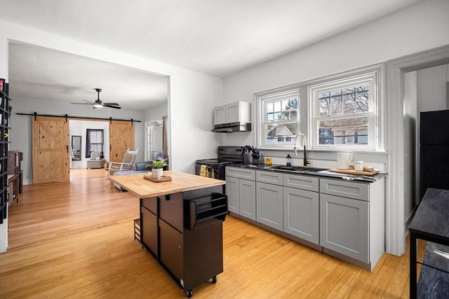 kitchen featuring sink, gray cabinets, black appliances, and a barn door