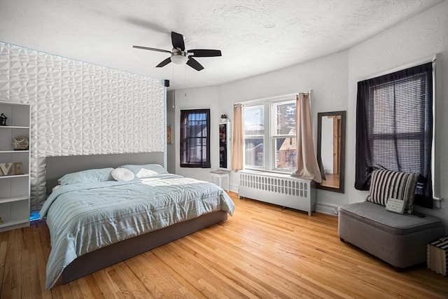 bedroom featuring hardwood / wood-style flooring, ceiling fan, radiator, and a textured ceiling